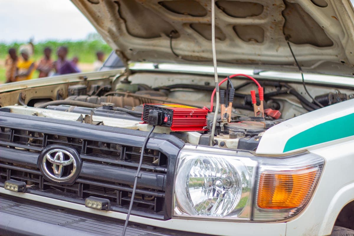 A battery charger connected under an open car hood